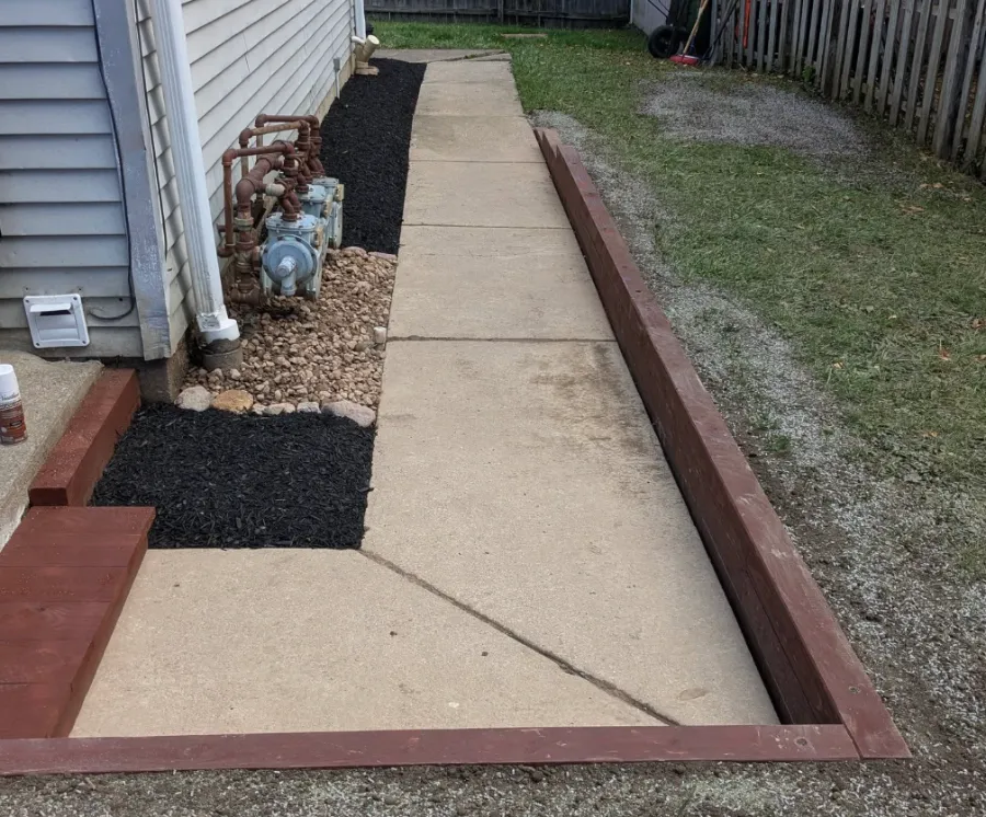 New side-yard bed with mulch and gravel along a walkway