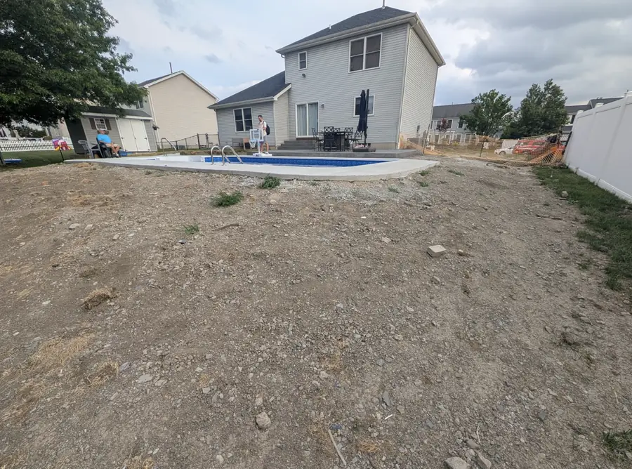 Backyard beside a new pool before grading, full of rock and patchy dirt